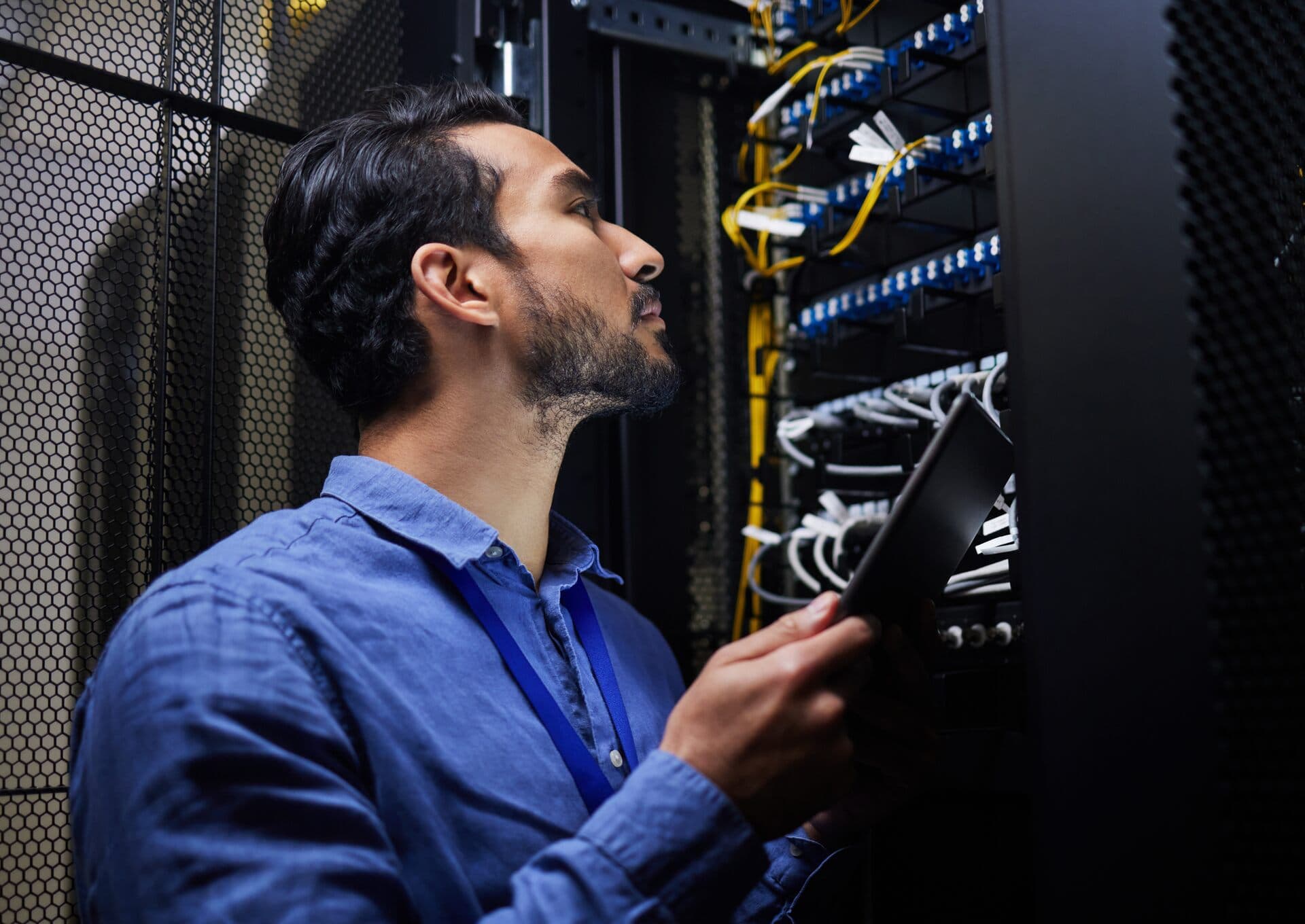 Técnico con tableta revisa los cables de red de un rack de servidores en un centro de datos