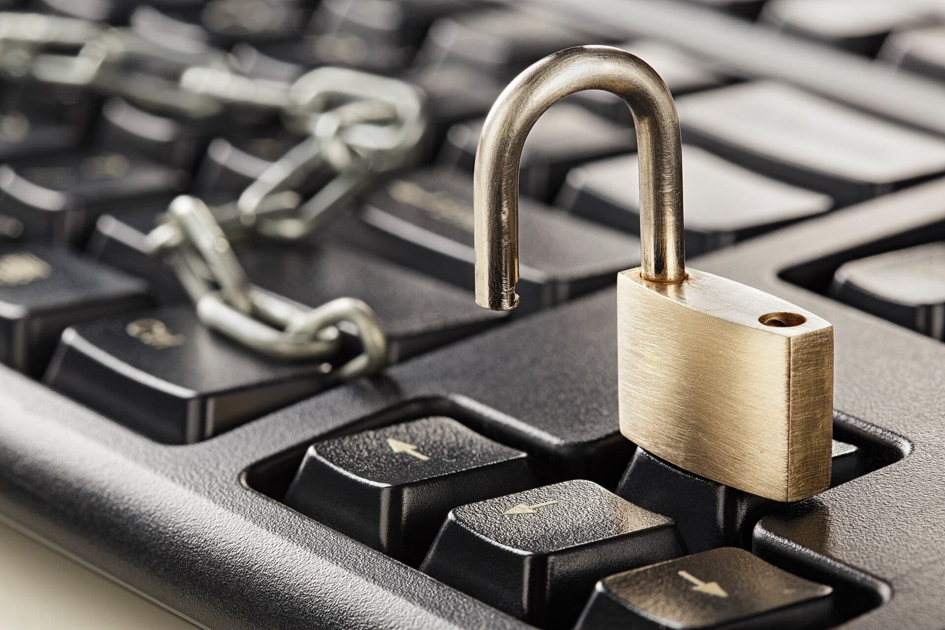 Candado abierto y una cadena sobre las teclas de un teclado de computadora