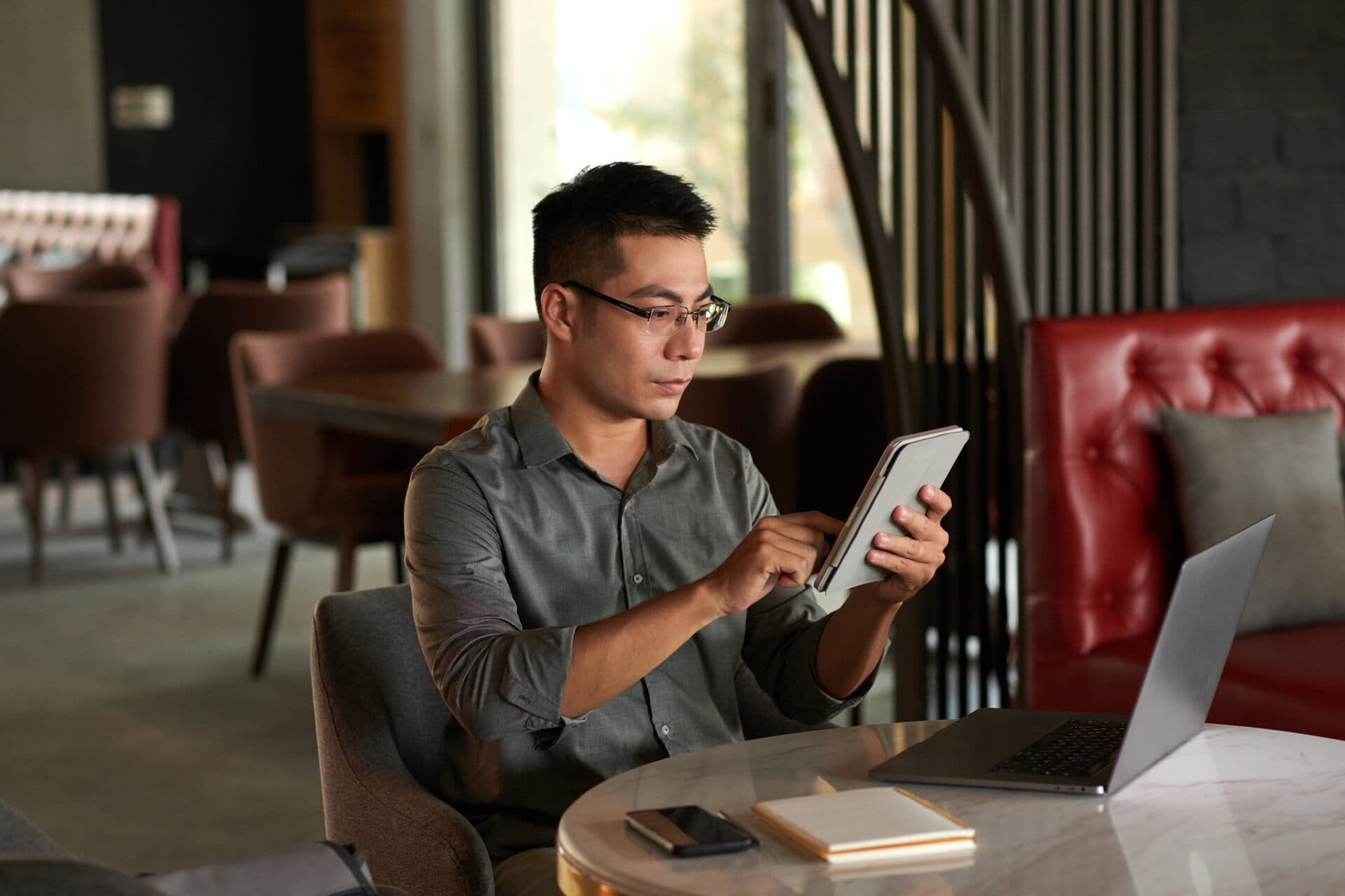 Emprendedor lee un artículo en la tablet en una cafetería