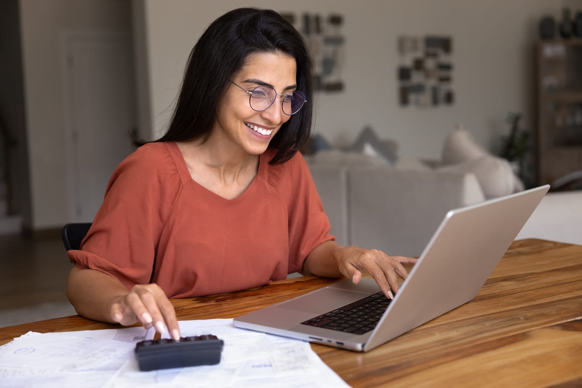 Contadora sonriente calcula un presupuesto con laptop y calculadora