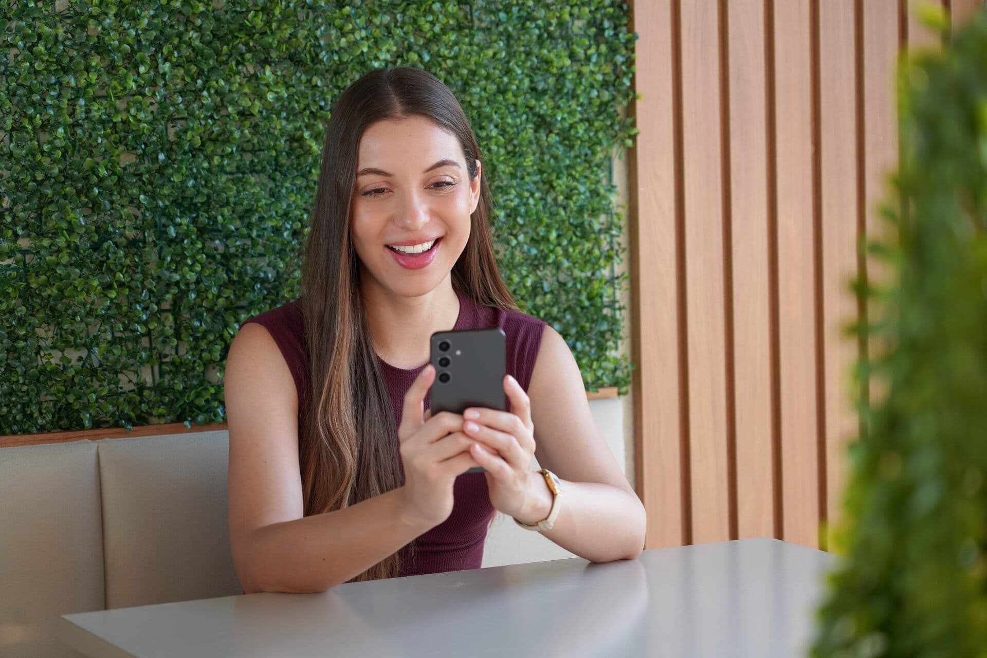 Mujer sonriente escribe en una app de mensajes desde una cafetería
